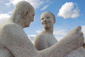 Skulptur fra Vigelandsparken av mann og dame med skyer og himmel i bakgrunnen.
